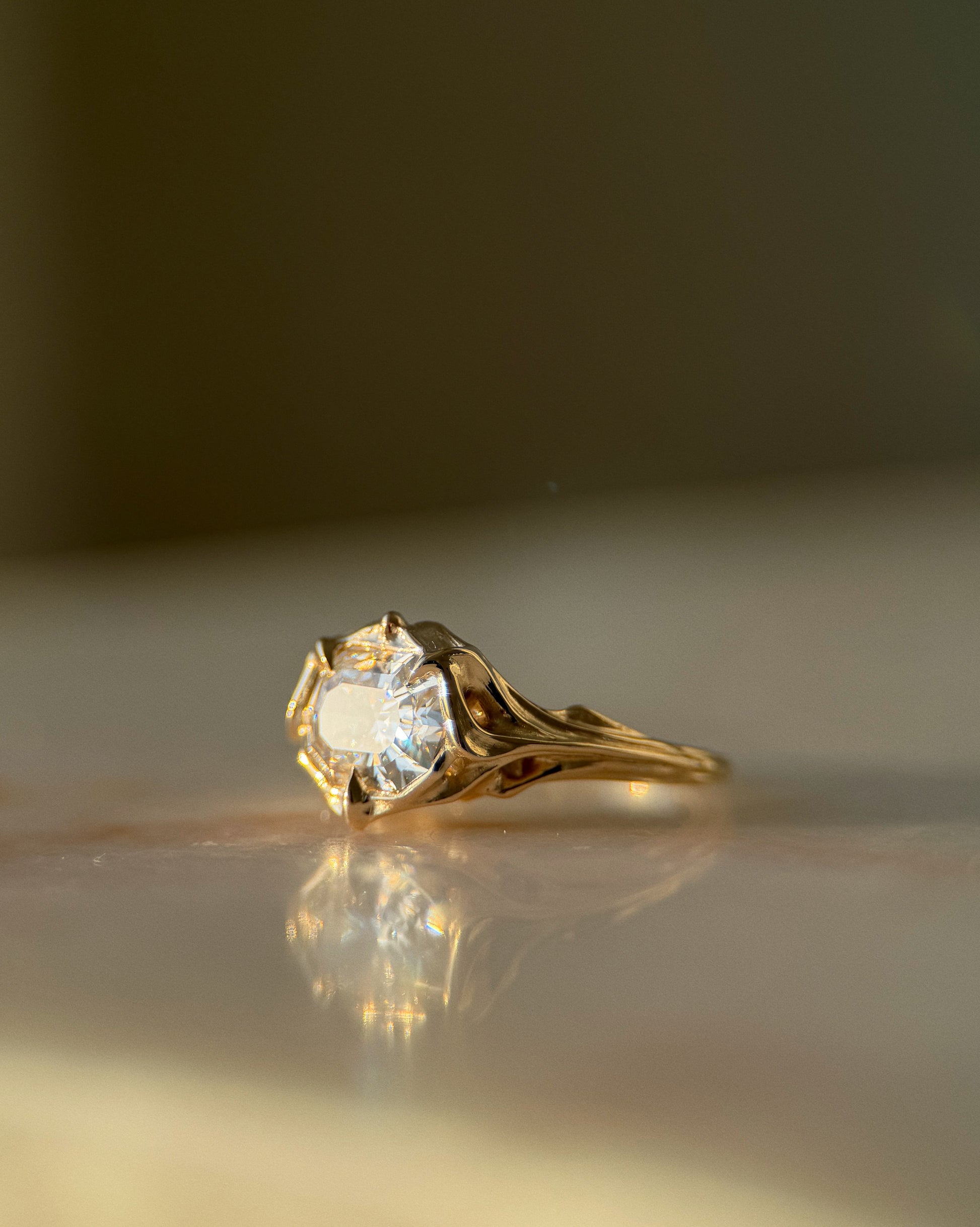 Gold ring with a diamond on a reflective surface
